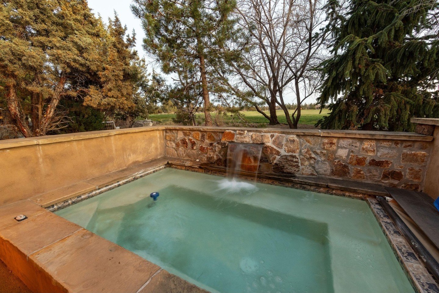 Outdoor spa and pool with stone surround at dusk, Brushline Ct, Pronghorn, Bend, Oregon